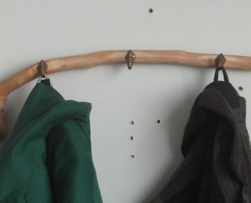 Bij deze kapstok versterken kleding en het natuurlijke hout en de antieke knoppen elkaar.